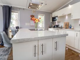 A kitchen with a large island counter and chairs at 155 Woodland Hall Lyons in Ruthin