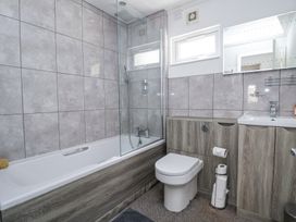 A bathroom with a bathtub shower toilet and sink with cabinets at 155 Woodland Hall Lyons in Ruthin