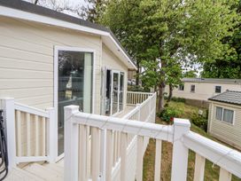 A balcony with white railing attached to a beige mobile home with trees and other mobile homes in the background at 155 Woodland Hall Lyons in Ruthin