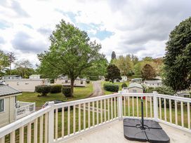 A view from a balcony overlooking a residential area with trees grass and mobile homes at 155 Woodland Hall Lyons in Ruthin