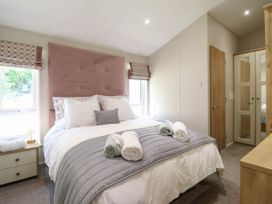 A bedroom with a bed with pillows and rolled towels beside bedside tables with lamps and a wardrobe at The Owlet in Dolwen near Llanidloes