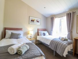 A bedroom with two single beds each with pillows and folded towels on gray blankets at The Owlet in Dolwen near Llanidloes