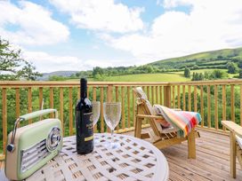A table with wine, glasses, and a radio on a deck at The Owlet in Dolwen near Llanidloes