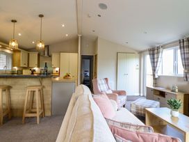 A living room with kitchen and bar stools at The Owlet in Dolwen near Llanidloes