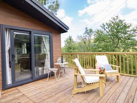 An outdoor deck area with wooden chairs and a small table at The Owlet in Dolwen near Llanidloes