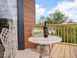 A table with a wine bottle and glasses on a balcony at The Owlet in Dolwen near Llanidloes