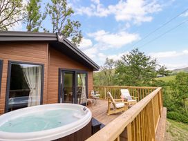 An outdoor deck with a hot tub and seating area at The Owlet in Dolwen near Llanidloes
