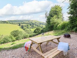 An outdoor area with a picnic table and a view of hills at The Owlet in Dolwen near Llanidloes