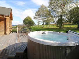 An outdoor area with a hot tub and wooden cabin at Dan Y Coed Beggar's Bush near Presteigne