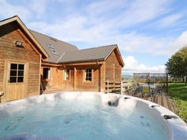 A hot tub near wooden house and outdoor seating area at Dan Y Coed near Presteigne