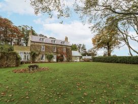 A house with a garden and trees at Elford Farmhouse Seahouses