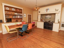 A kitchen with a wooden table and colorful chairs at Elford Farmhouse in Seahouses