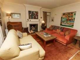 A living room with a sofa, armchair, and fireplace at Elford Farmhouse in Seahouses