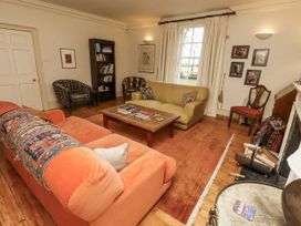 A living room with a sofa, armchair, and fireplace at Elford Farmhouse in Seahouses