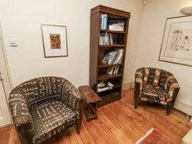 A sitting room with two armchairs and a bookshelf at Elford Farmhouse Seahouses