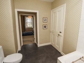 A bathroom with a toilet and door at Elford Farmhouse in Seahouses