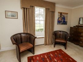 A sitting room with two chairs and a window at Elford Farmhouse Seahouses