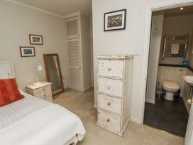 A bedroom with a bed, mirror, and chest of drawers at Elford Farmhouse Seahouses