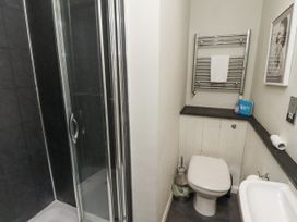 A bathroom with a shower, toilet, towel rail, and sink at Elford Farmhouse in Seahouses