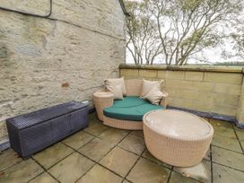 An outdoor patio with a sofa, round table, and storage box at Elford Farmhouse in Seahouses