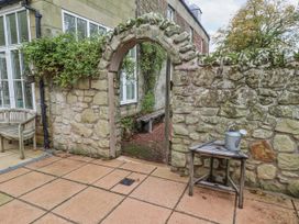 A garden area with a stone wall and a wooden bench at Elford Farmhouse in Seahouses