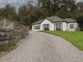 A house with a gravel driveway and stone wall at The Lodge in Bridgend