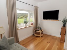 A living room with a sofa, television, and window at The Lodge in Bridgend