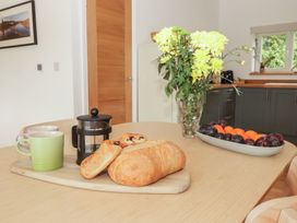 A kitchen with a table, coffee cups, bread, and a fruit bowl at The Lodge in Bridgend