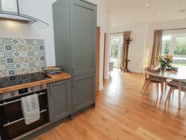 A kitchen with a stove, cabinets, and dining area at The Lodge in Bridgend