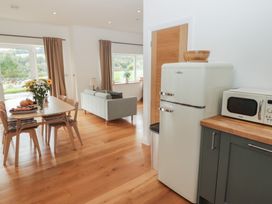 A kitchen with a refrigerator and a table at The Lodge in Bridgend