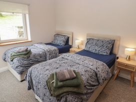 A bedroom with two single beds and a window at The Lodge in Bridgend