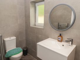 A bathroom with a toilet, wash basin, and mirror at The Lodge in Bridgend