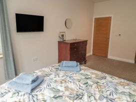A bedroom with a bed and a dresser at The Lodge in Bridgend