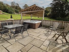 An outdoor area with a hot tub and seating at The Lodge in Bridgend