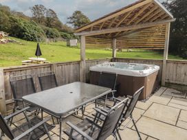 A hot tub and dining area with a table and chairs at The Lodge in Bridgend