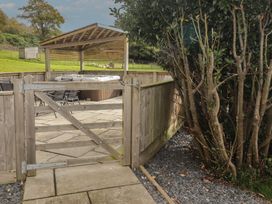 A garden with a hot tub and wooden gate at The Lodge in Bridgend