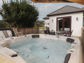 An outdoor area with a hot tub and table with chairs at The Lodge in Bridgend