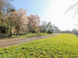 A garden with trees and a house at The Lodge in Bridgend