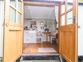 A small kitchen and dining area with wooden floors and open double doors at Sika in Warmwell