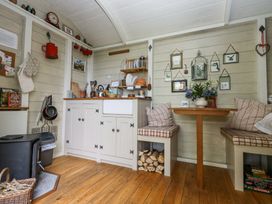 A small kitchen and dining area with wooden floor cabinets dishes and a wood stove at Sika in Warmwell