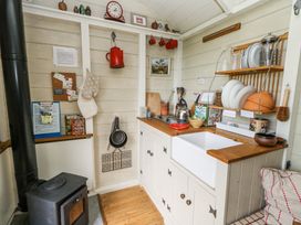A small kitchen with a wood stove and sink with dishes on a rack at Sika in Warmwell