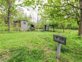 A grassy outdoor area with trees wooden huts and a sign reading Fallow at Warmwell