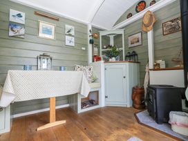 A small dining area with a table and bench seating next to a black wood stove and cabinets at Fallow in Warmwell