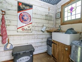 A utility room with a sink a stained glass window a red cloth a wall sign and metal trash bins at Fallow Warmwell