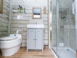 A bathroom with a toilet sink with cabinet and a glass shower at Fallow in Warmwell