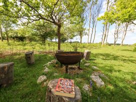 A fire pit with stone seats around it in a grassy area with trees and a book on a tree stump at Fallow in Warmwell