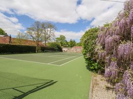 An outdoor tennis court with a net and surrounding greenery at Fallow in Warmwell