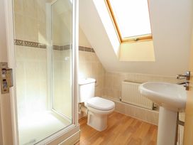 A bathroom with a shower, toilet, sink, and window at Farthings in Weymouth