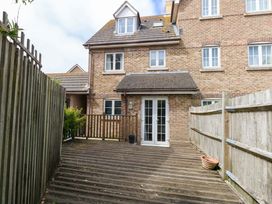 An outdoor area with a wooden deck and a house at Farthings in Weymouth