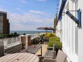 An outdoor patio with tables benches chairs umbrella and plants overlooking the sea at The Burleigh in Hunstanton